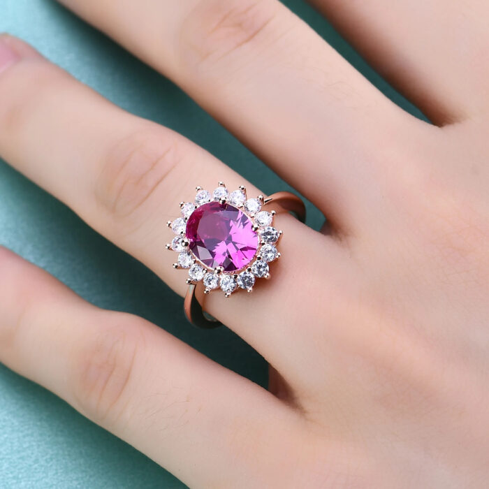 A hand model showcasing the Princess Diana inspired pink sapphire ring, highlighting its vibrant color and intricate design.